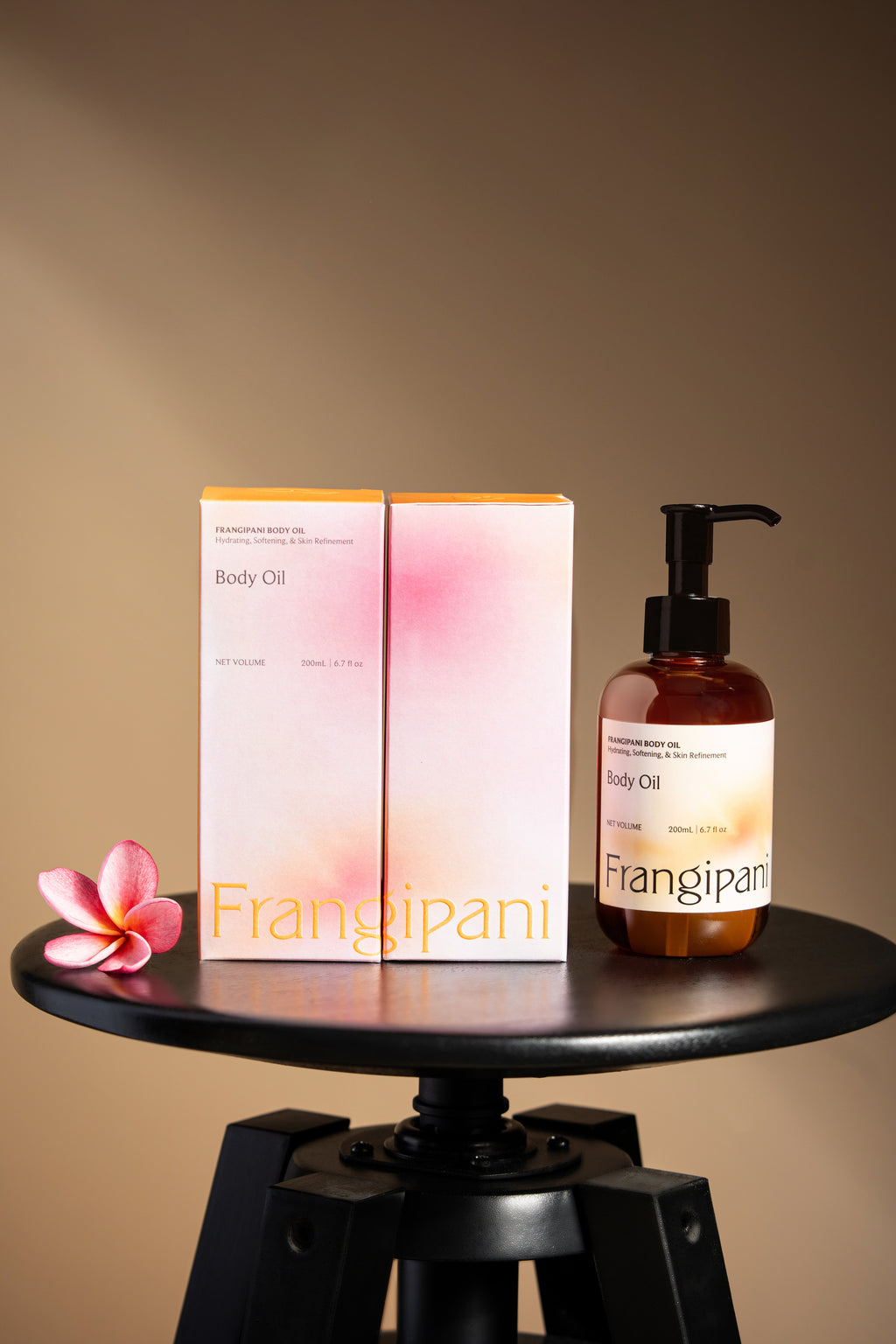 Frangipani body oil bottle and boxes displayed on a black stool