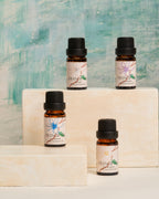 Four Frangipani essential oil bottles displayed on cream stone blocks