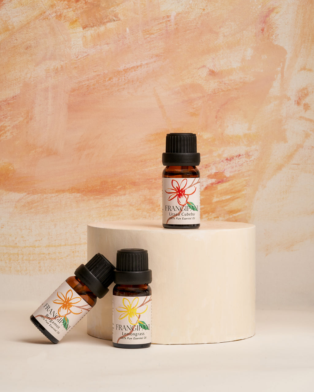 Frangipani Litsea Cubeba and Lemongrass oils staged on a cream pedestal