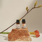 Frangipani Hinoki and Bergamot oil bottles on a rock with a magnolia branch