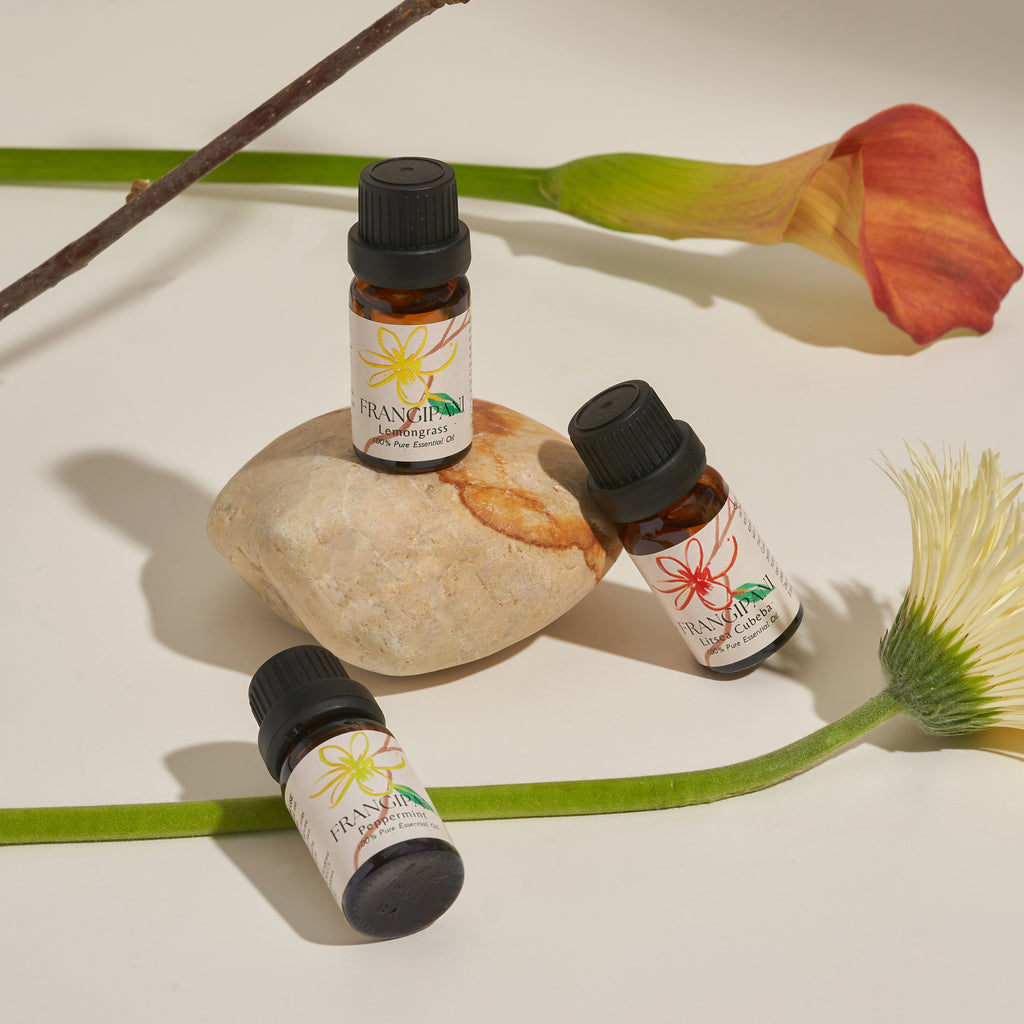 Three Frangipani essential oils styled with a calla lily and daisy