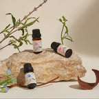 Three Frangipani essential oil bottles styled on a stone with fresh botanicals