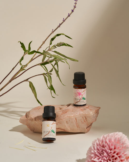 Frangipani Cedarwood and Eucalyptus oils on a stone with a pink dahlia
