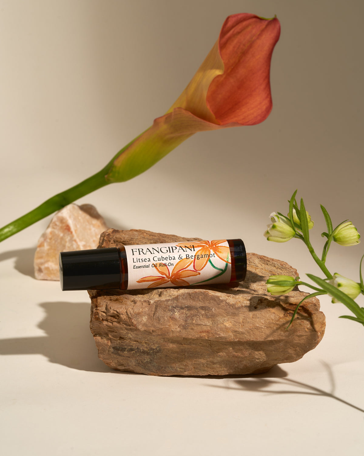 Frangipani Litsea Cubeba & Bergamot roll-on on rocks with a calla lily