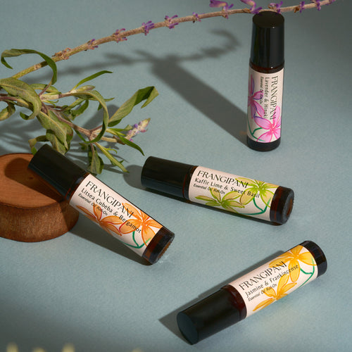 All four Frangipani essential oil roll-ons styled with lavender sprigs