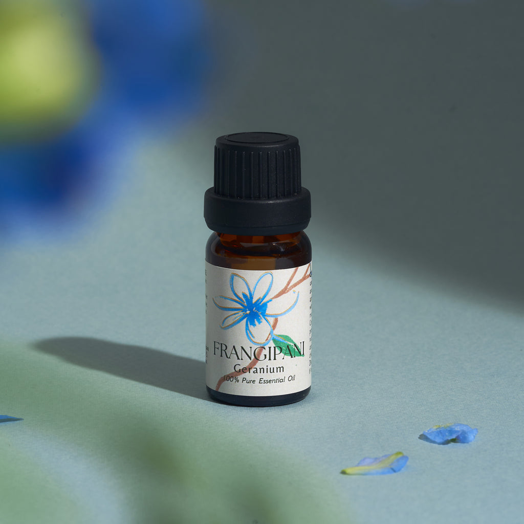 Frangipani Geranium essential oil bottle with scattered blue petals