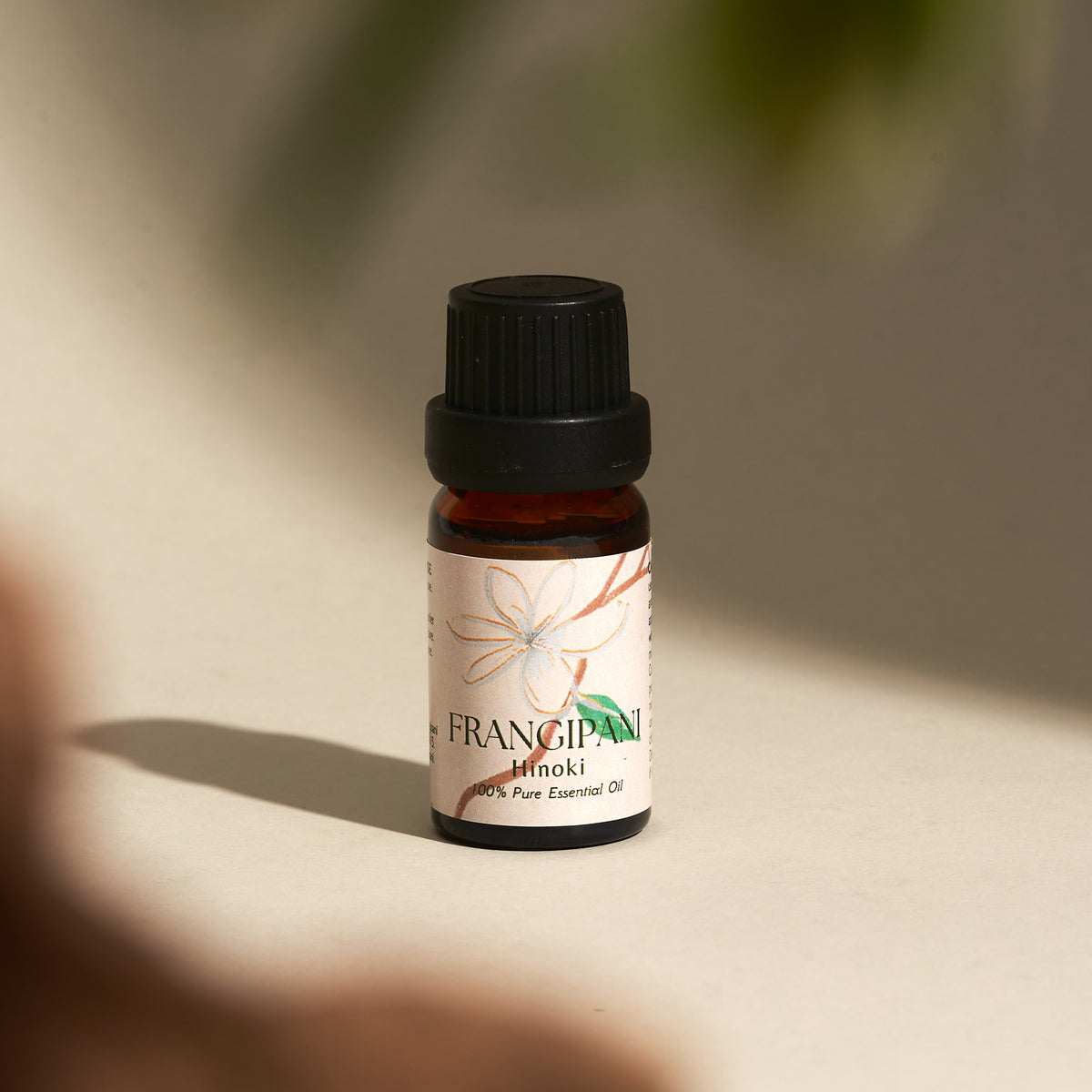 Frangipani Hinoki essential oil bottle in dappled natural light