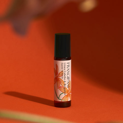 Frangipani Litsea Cubeba & Bergamot roll-on on a vivid orange backdrop