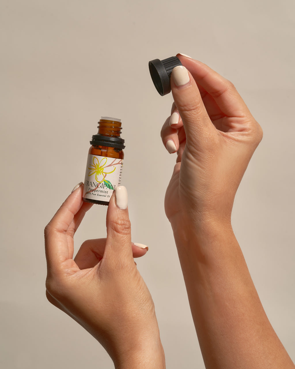 Hands opening a bottle of Frangipani Peppermint essential oil