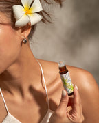 Woman with a plumeria in her hair holding a Frangipani roll-on