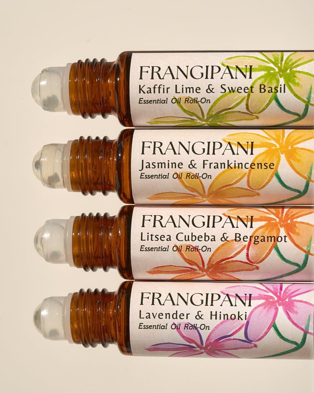 Close-up of four Frangipani roll-on scents with hand-painted floral labels