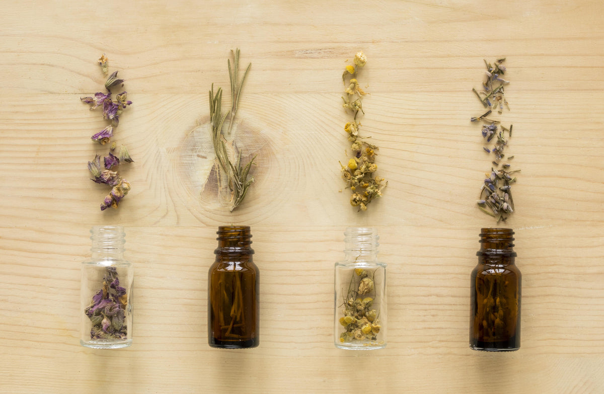 Four small glass bottles with herbs on a wooden surface