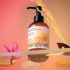 Frangipani body oil on a shelf with plumeria, dried grass, and lemon slices